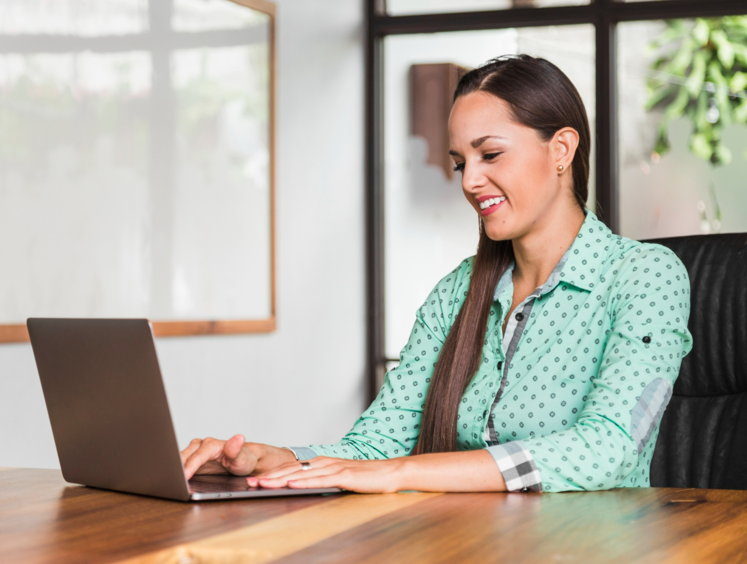 Woman smiling while using a laptop in a modern office setting, representing business compliance and data privacy discussions related to the California Consumer Privacy Act (CCPA) and California Privacy Rights Act (CPRA).