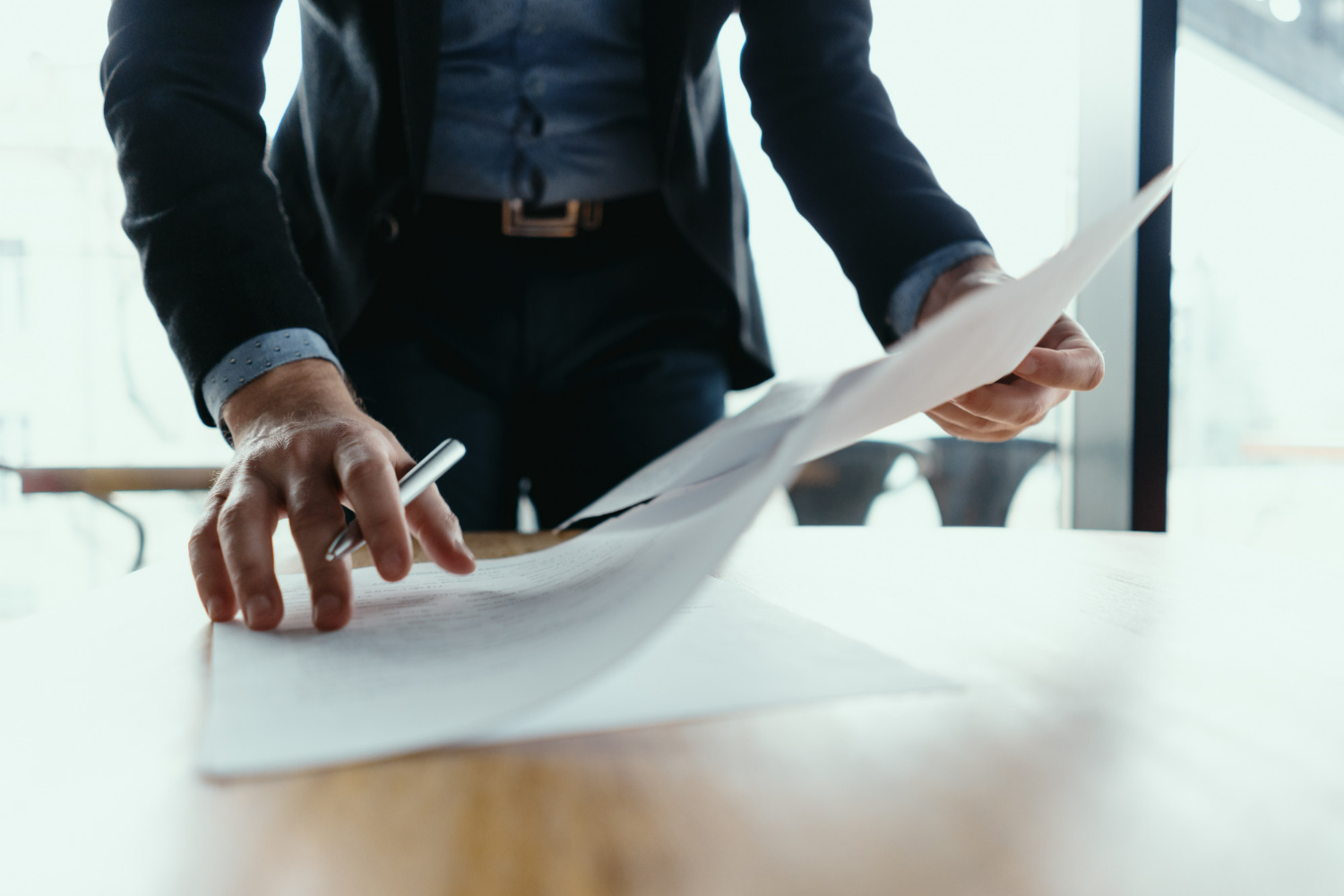 Person reviewing legal documents on a table, emphasizing the importance of understanding zoning laws and real estate regulations.