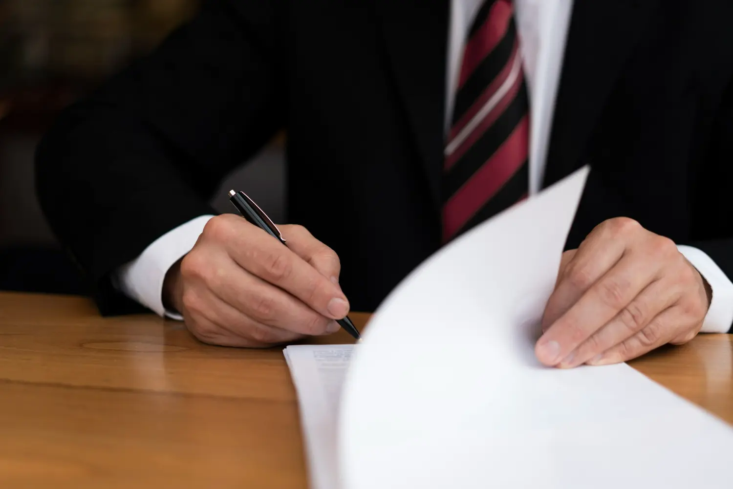 Business attorney signing legal documents on a wooden table, emphasizing the importance of legal guidance in dispute resolution and arbitration.