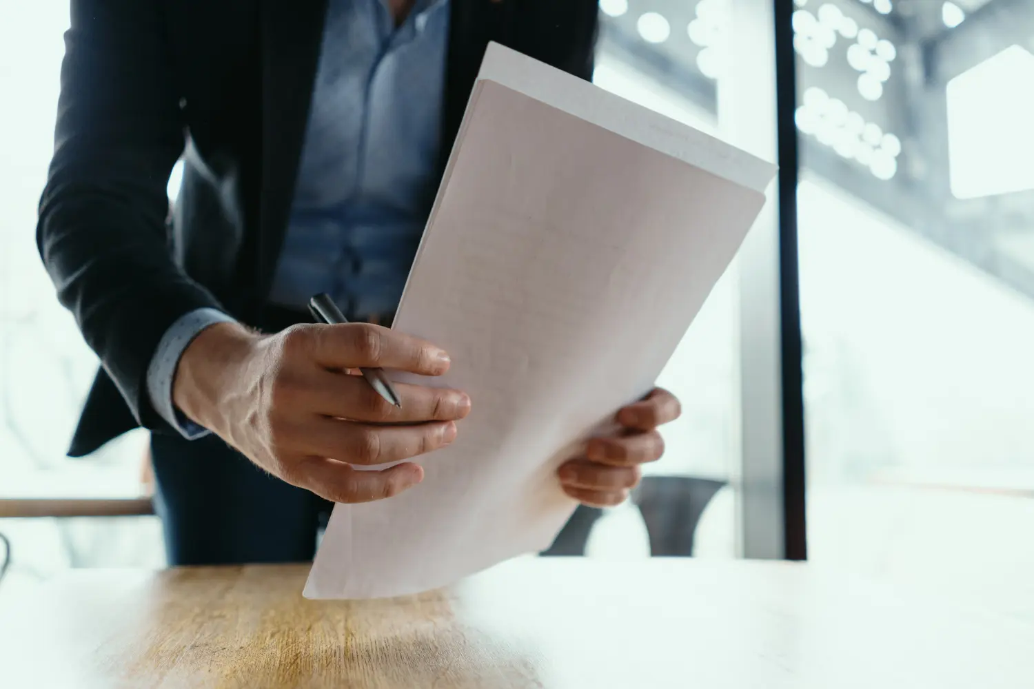 Person in a suit holding legal documents and a pen, illustrating the process of filing a quiet title action in California.
