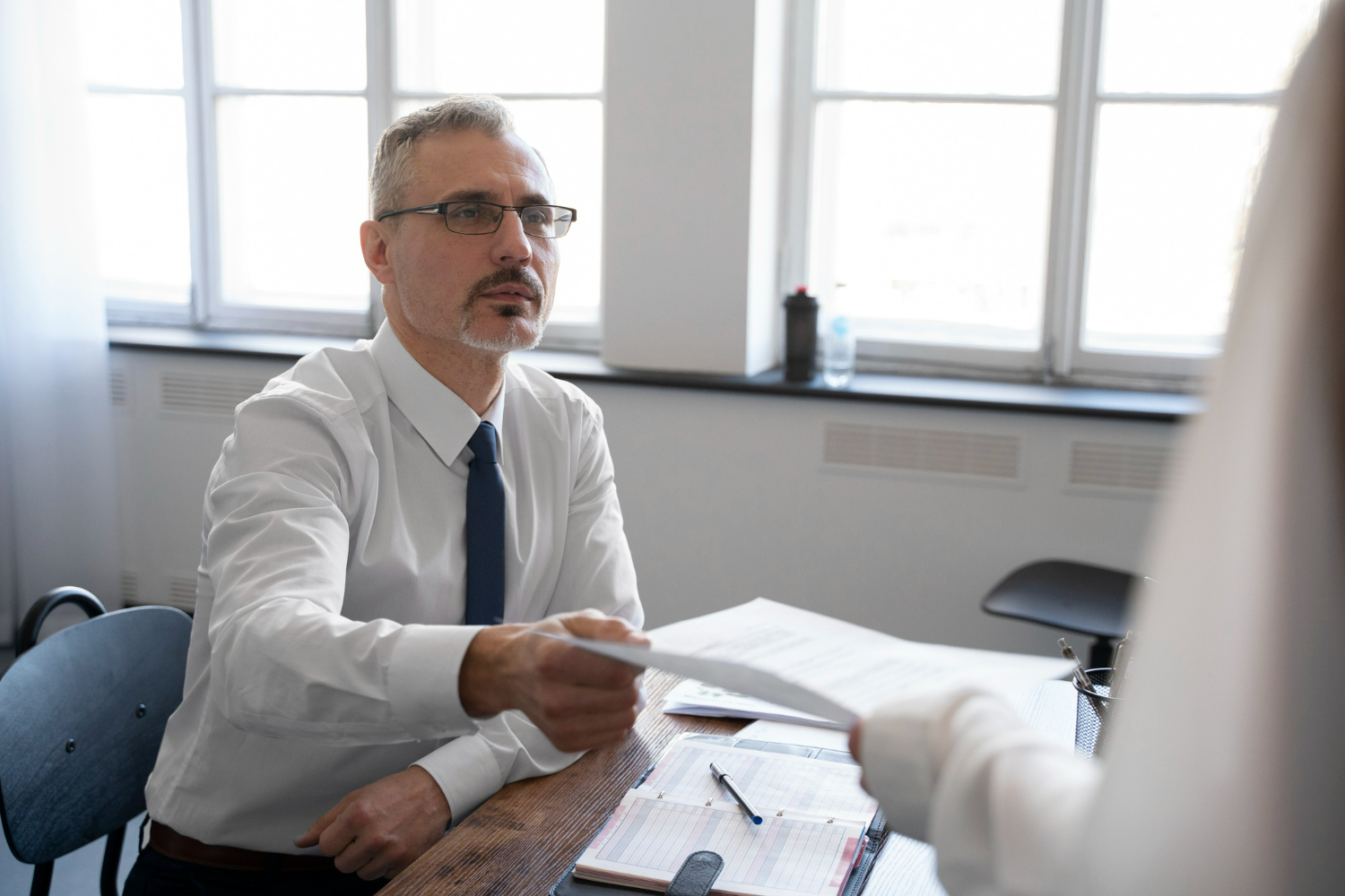 Man in a white shirt and tie receiving documents in an office setting, symbolizing legal guidance during real estate transactions in Carlsbad.