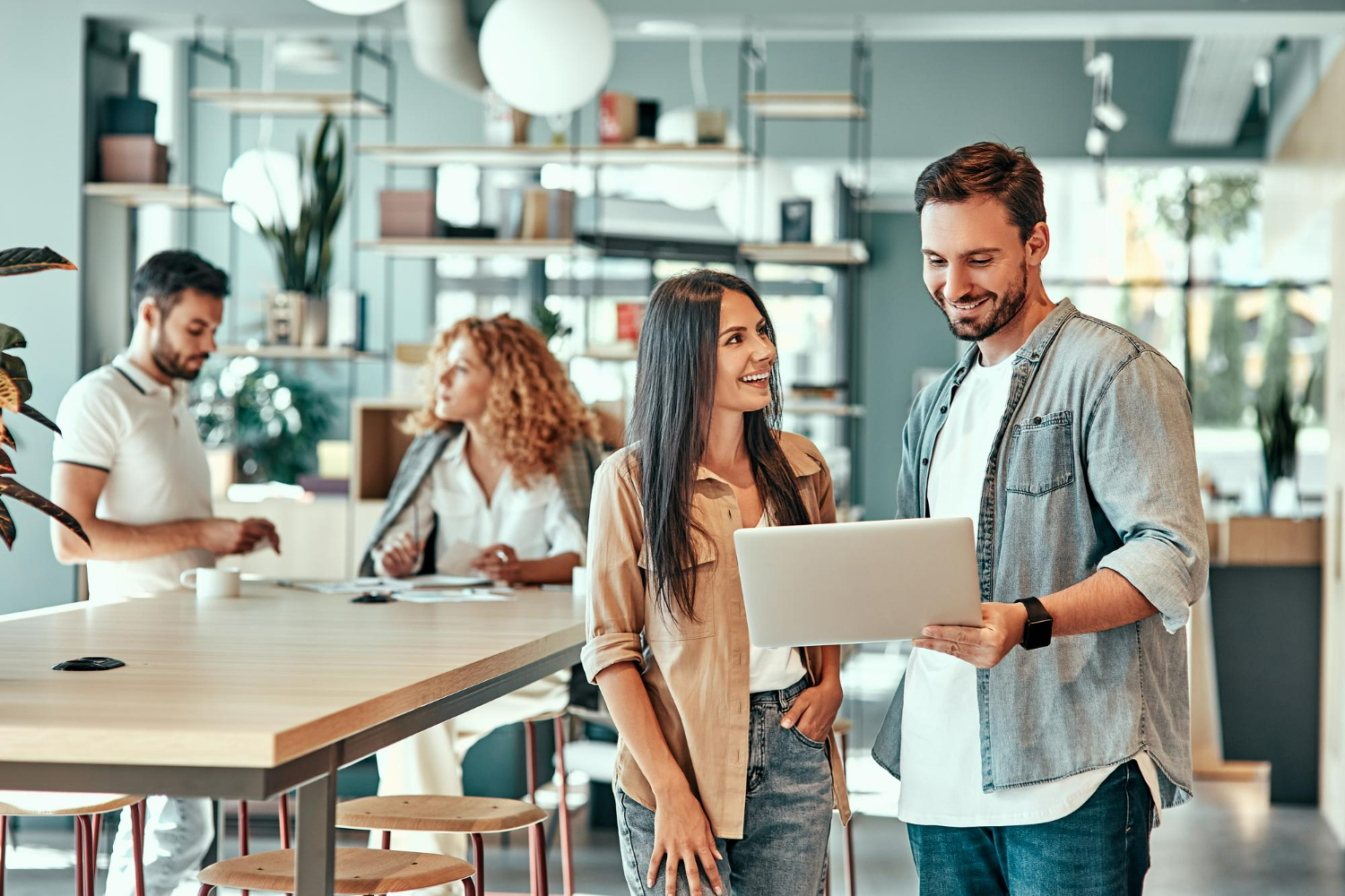 Two professionals discussing over a laptop in a modern office setting, with a focus on collaboration and teamwork, reflecting the importance of effective management structures for LLCs.