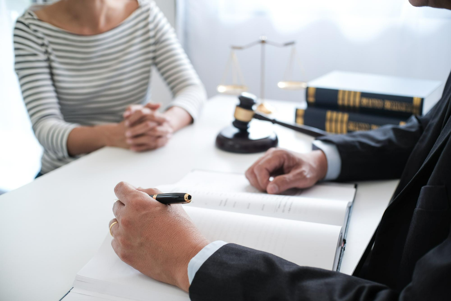 Lawyer consulting with client over legal documents, gavel and law books in background, emphasizing real estate transaction guidance and compliance in Carlsbad, California.
