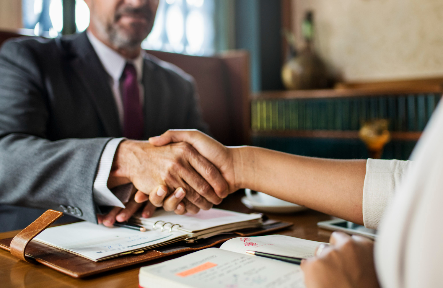 Lawyer and client shaking hands at a table with legal documents, symbolizing the importance of real estate closing attorneys in California property transactions.