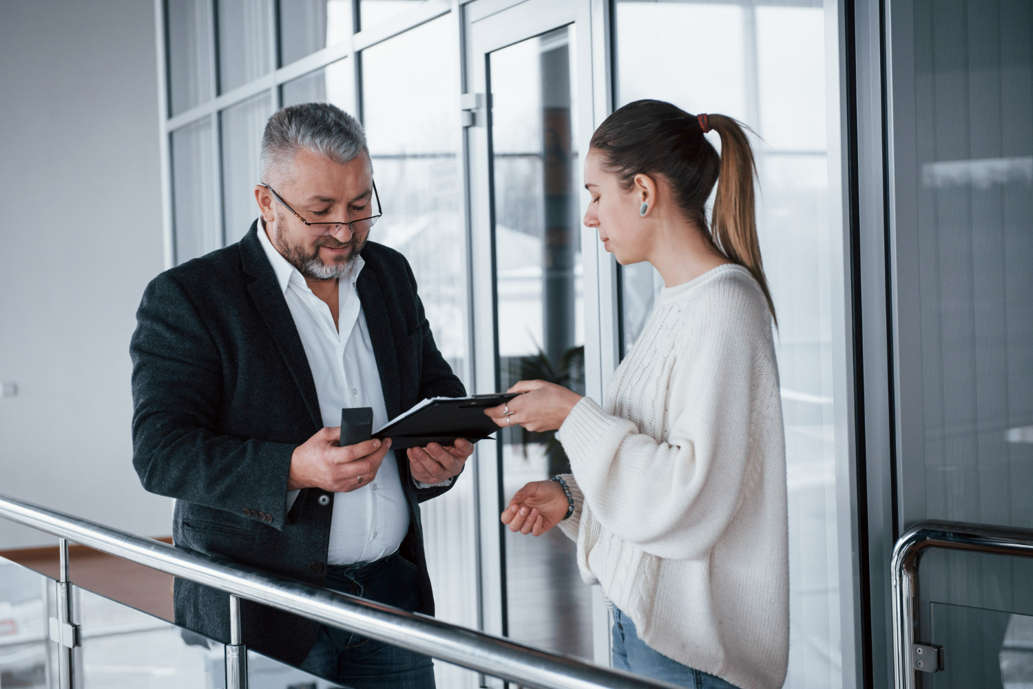 Man in a blazer discussing documents with a woman in a sweater, emphasizing communication and responsiveness in real estate legal matters.