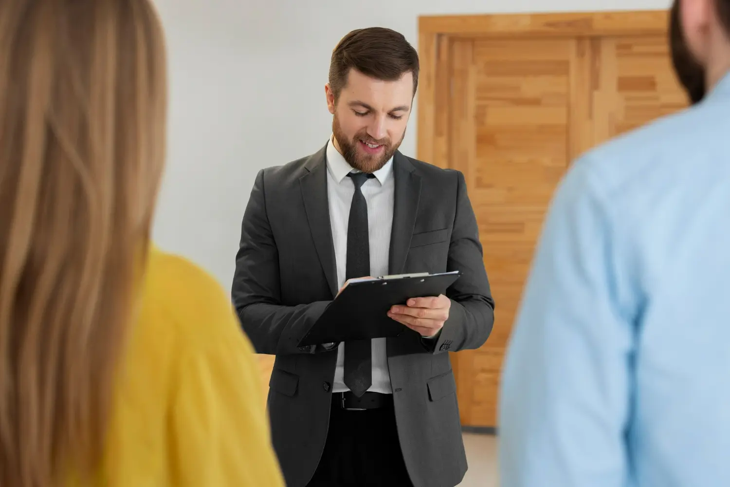Real estate attorney in suit discussing contract details with clients in a professional setting.
