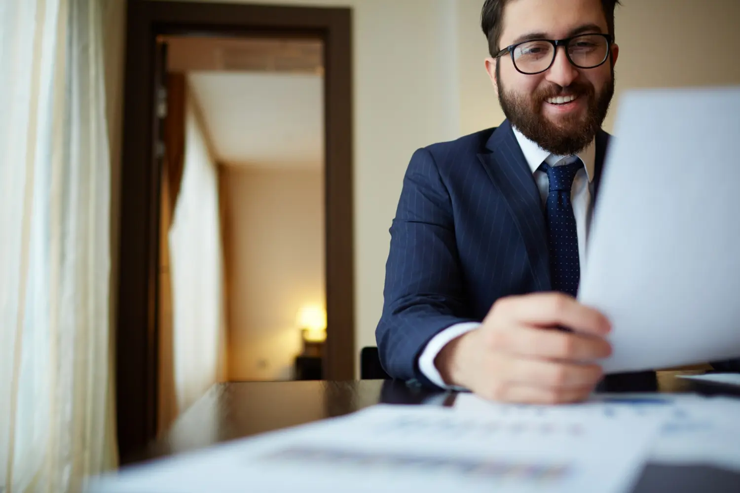 Man in a suit reviewing documents on a table, symbolizing legal consultation and real estate services in Carlsbad.