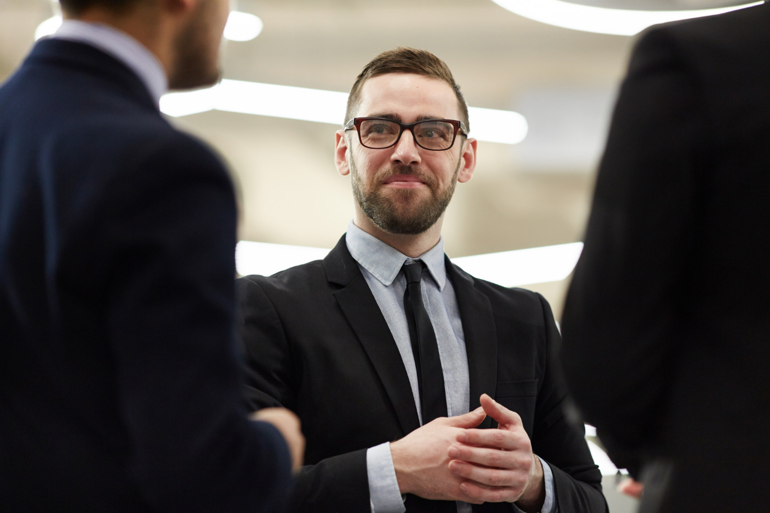 Business professional engaging in conversation, wearing glasses and a suit, in a modern office setting, relevant to business law and attorney services in San Diego.