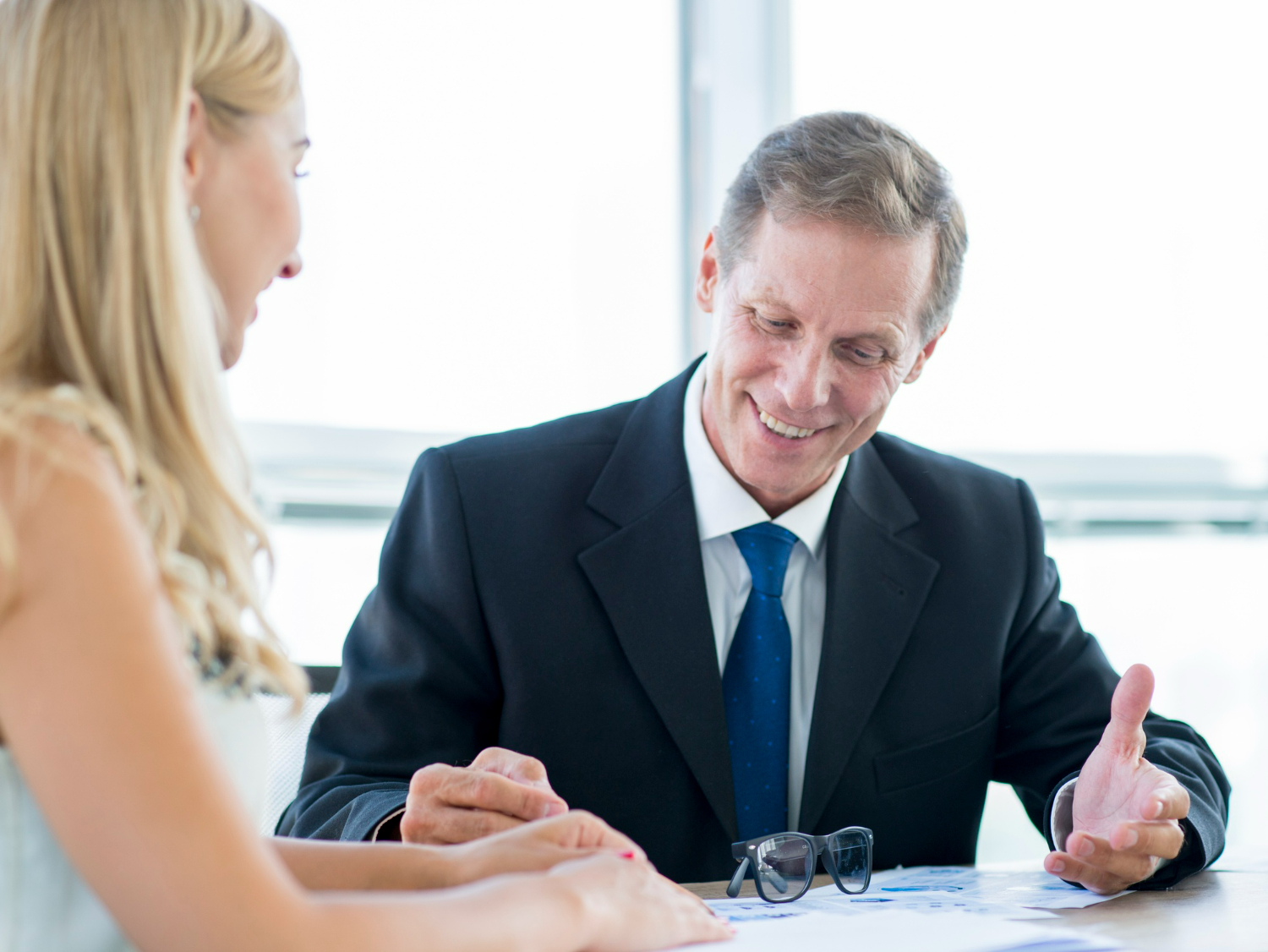 Business attorney consulting with client, discussing legal strategies and documents related to confidentiality and intellectual property protection in a professional office setting.