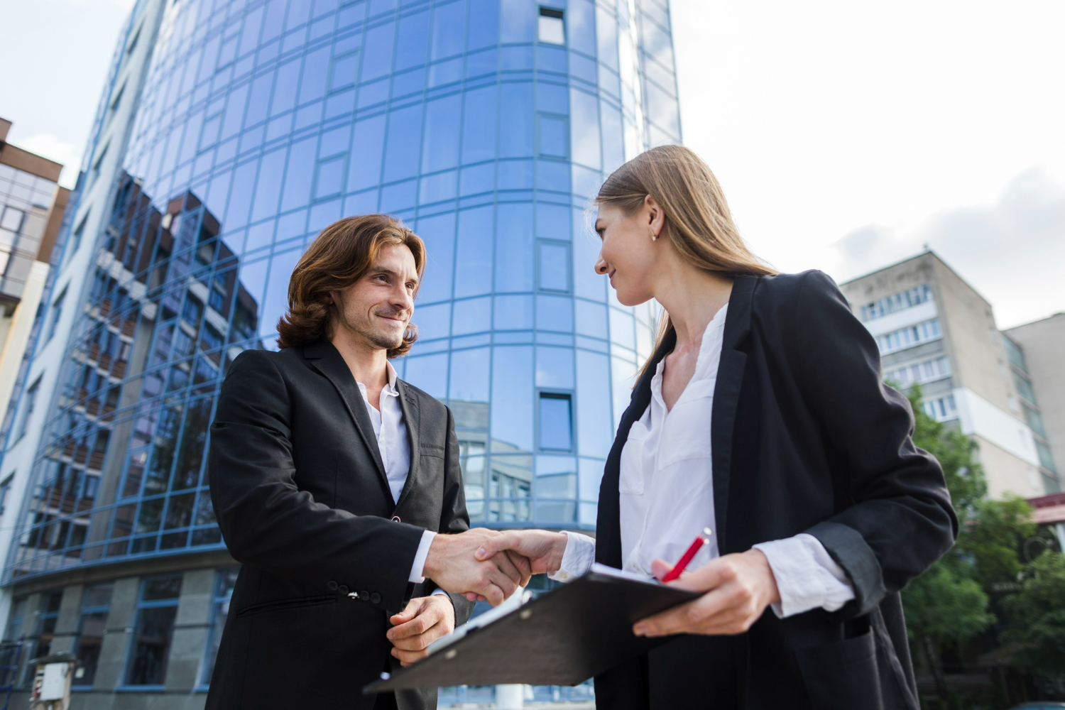 Commercial real estate buyer and advisor shaking hands during a due diligence review outside an office building