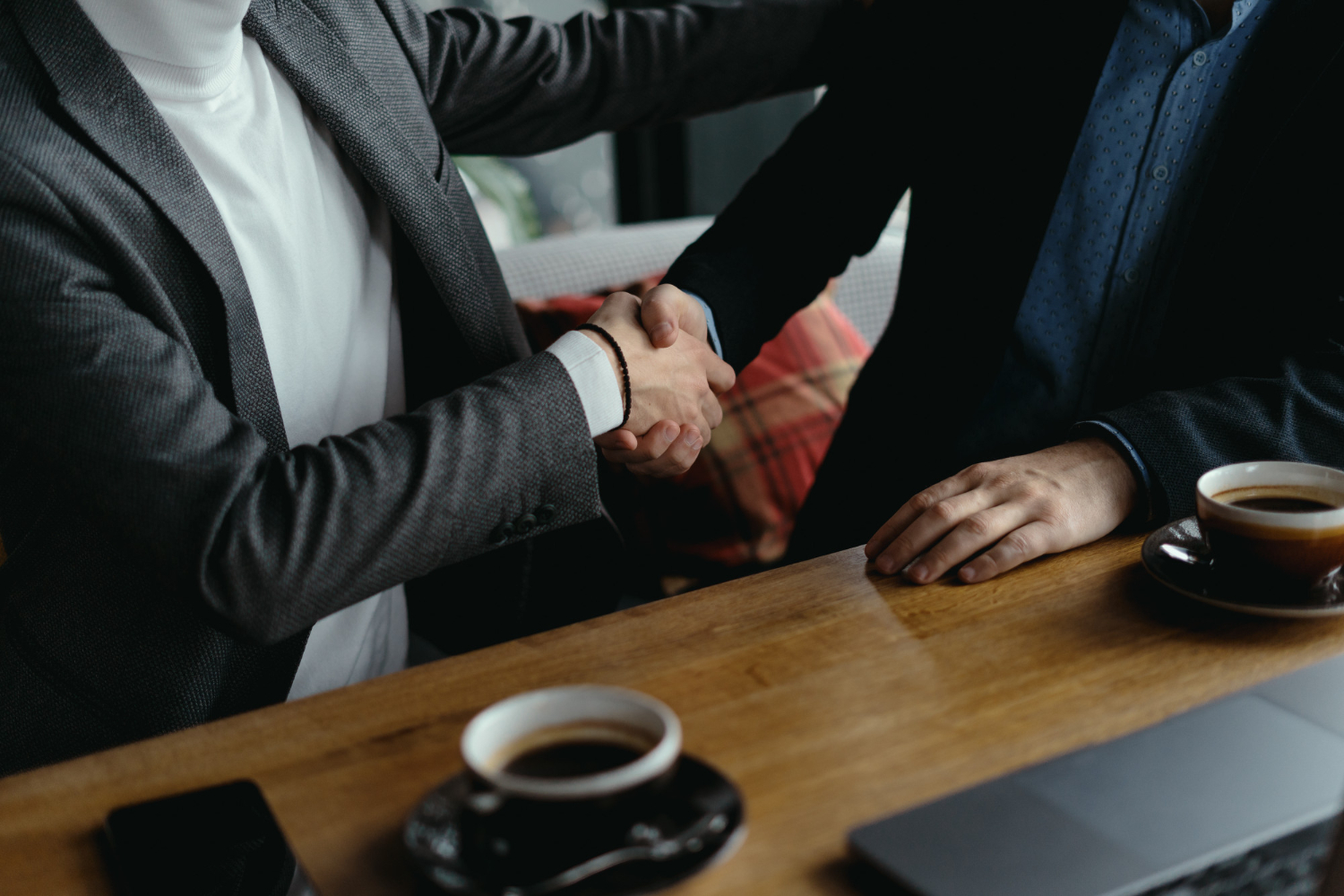 two professionals shaking hands at a table during a business meeting, symbolizing a legal consultation or professional agreement
