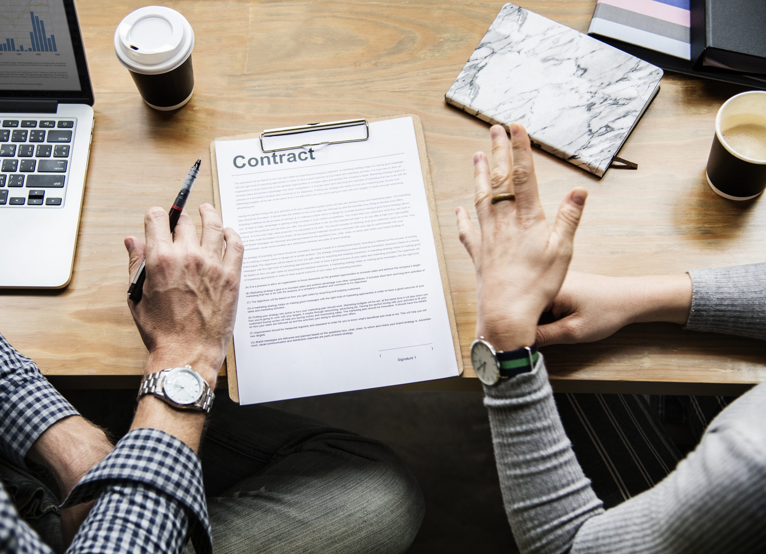 Two professionals reviewing a contract in a table with coffee