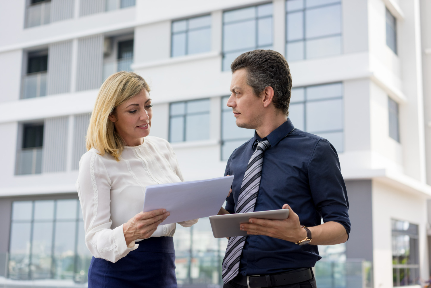 Business professionals reviewing commercial lease documents outside an office building
