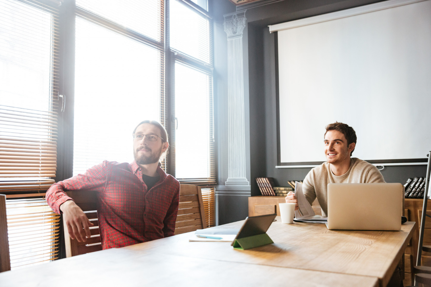 Two professionals discussing options in an office setting, highlighting key legal considerations when deciding between buying or leasing a first office space
