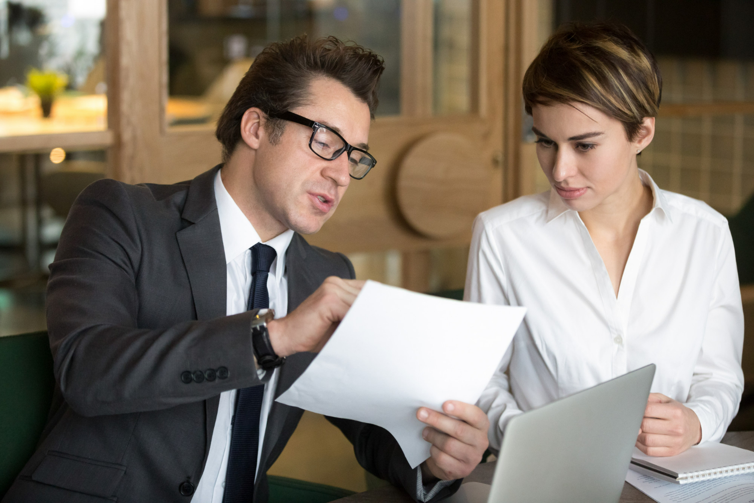 A business professional reviewing contract terms and transaction documents with a client during a commercial deal consultation