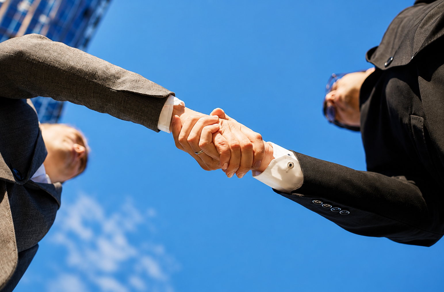 Two suited professionals shaking hands outdoors, symbolizing a business partnership agreement and the fiduciary duties partners owe each other under California law